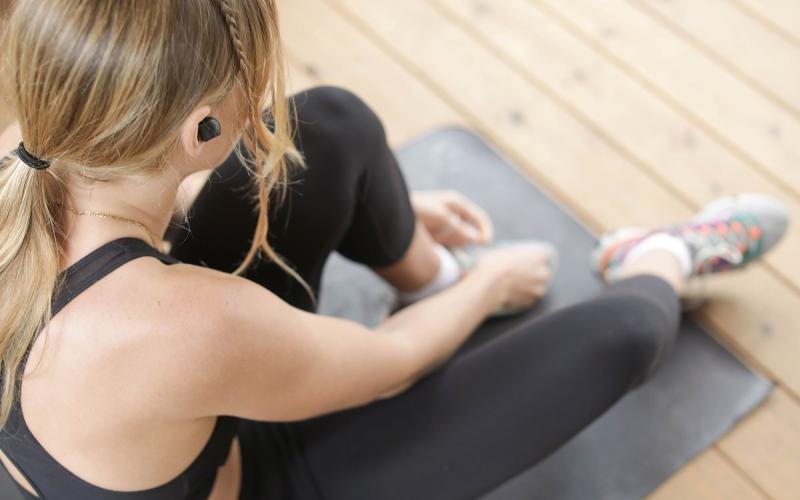 Get your workout on woman in workout gear, sits on a yoga mat and ties her shoe