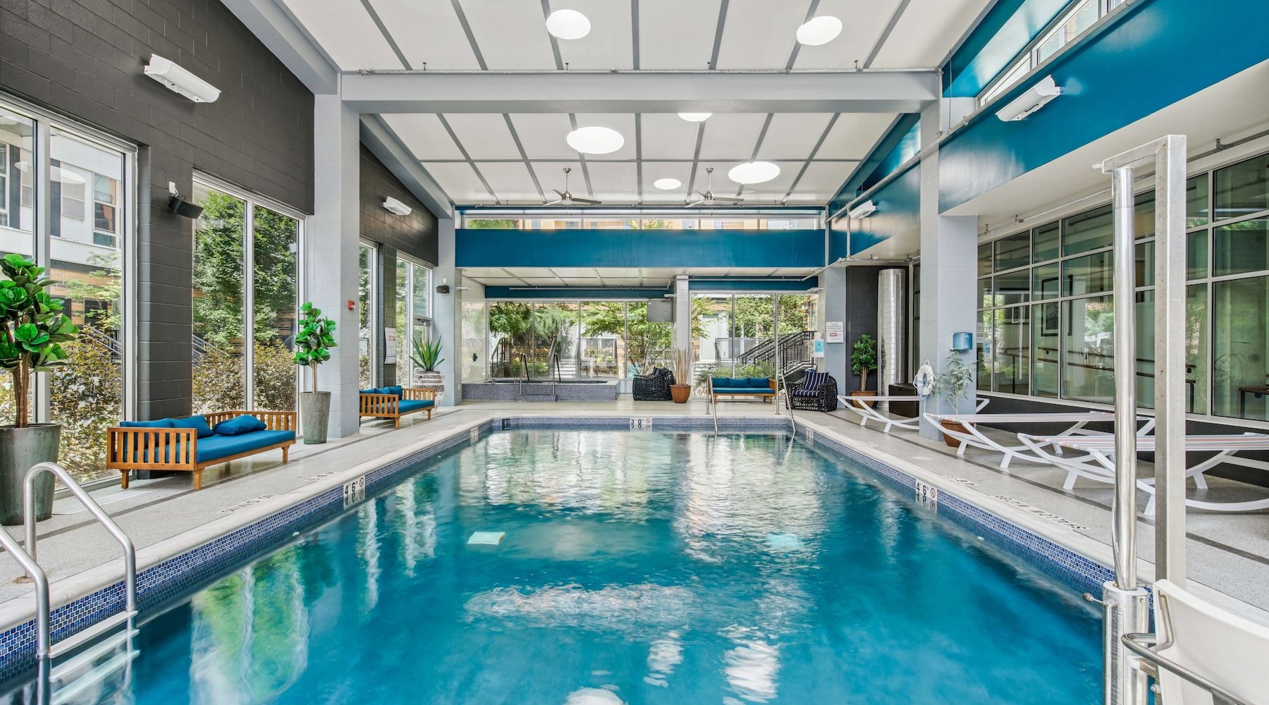 The indoor pool at Albion at Morrow Park Apartments in Pittsburgh, PA, featuring lounge chairs and couches.
